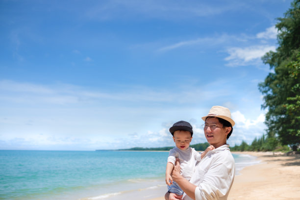 可爱的1岁/ 18个月蹒跚学步的亚洲小男孩在白色沙滩上亲吻爸爸图片下载