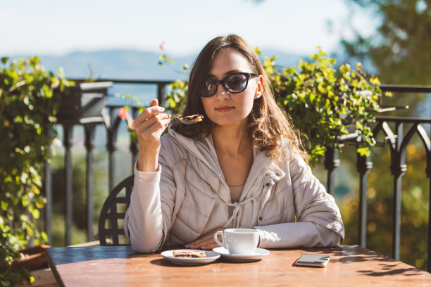 年轻女子在舒适的意大利咖啡馆吃蛋糕和喝咖啡的肖像-度假和健康食品的概念图片下载