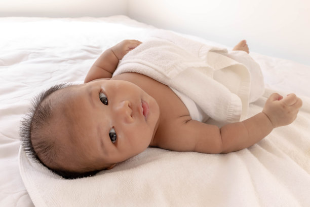 新生儿仰卧着睡觉，在白色的床垫上玩的心情很好，在睡觉的时候，孩子的大脑会工作。增强增强记忆和学习能力图片下载
