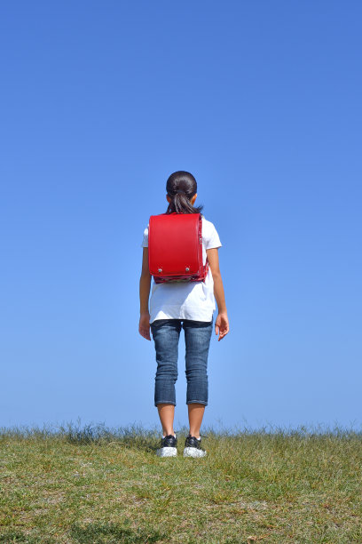 日本女小学生站在蓝天上(后视图)图片下载