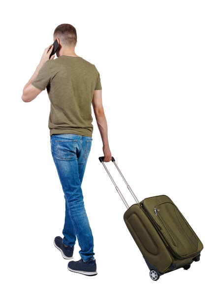 带着行李箱走路的人用智能手机说话的背影。图片下载