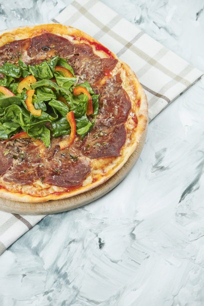 多汁的意大利自制披萨，配以意大利小牛肉和菠菜叶，配以红酱和马苏里拉奶酪在灰色背景上。图片下载