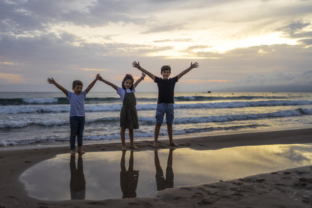 日落时分，三个孩子在海滩上图片下载