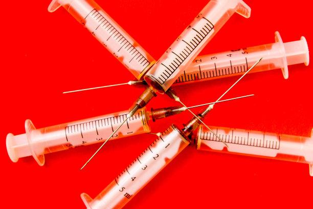 红色背景上是用过的注射器。海洛因的流行病。制备治疗性药物，发生注射、海洛因、毒品等。阿片类药物流行病。图片下载