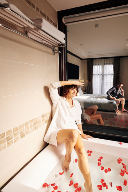 微笑的漂亮女人在沐浴与花瓣摆姿势图片下载