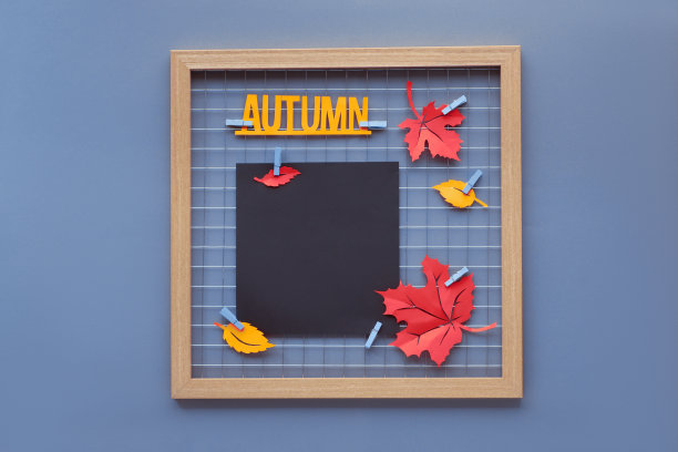 黑色纸模型为您的字母，书法或照片。照片网格板与火焰猩红和藏红花黄色纸秋天的叶子和文字“秋天”的钉子。图片下载