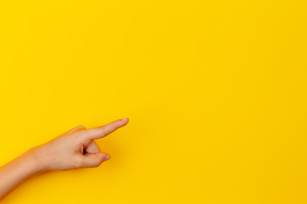 孩子的手指着黄色背景上的东西图片下载