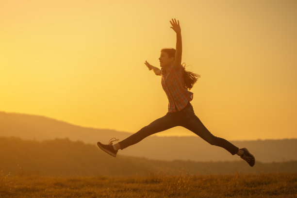 快乐的孩子在夕阳中跳跃。图片下载