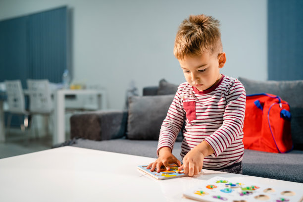 小男孩独自在家玩小游戏，在桌子旁玩拼图，发展智力，有乐趣的学习图片下载