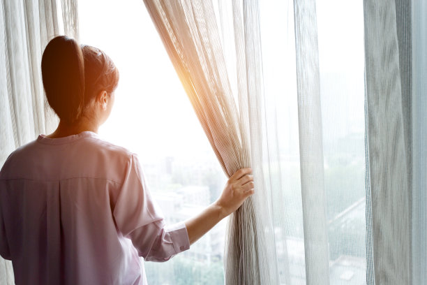 女人拉开窗帘向外看素材图片