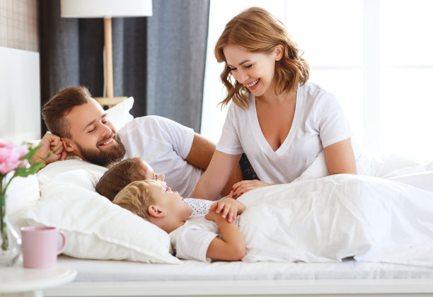 幸福的家庭妈妈，爸爸和孩子们笑着，在家里的床上玩着，笑着图片下载