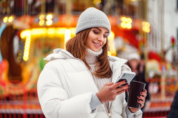 一个美丽的年轻女人或女孩使用电话户外圣诞假期背景图片下载