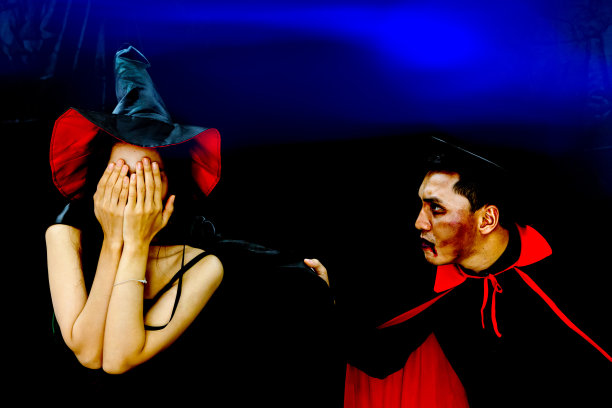 女巫女人害怕和掩盖她的脸与手从男性吸血鬼在深蓝色的背景在万圣节派对图片下载