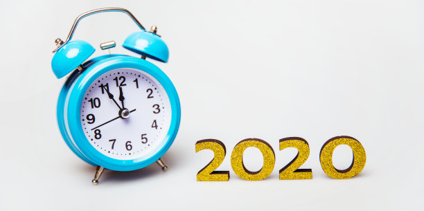 击败了时钟。一个天蓝色闹钟的特写照片，放在照片的左边，靠近2020的金色数字。新年的概念图片下载