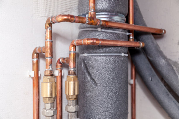 特写许多铜和下水道灰色塑料管道，红色阀门，配件在混凝土墙上。概念安装、更换、水管、维修管道，专业管道工、漏水管图片下载
