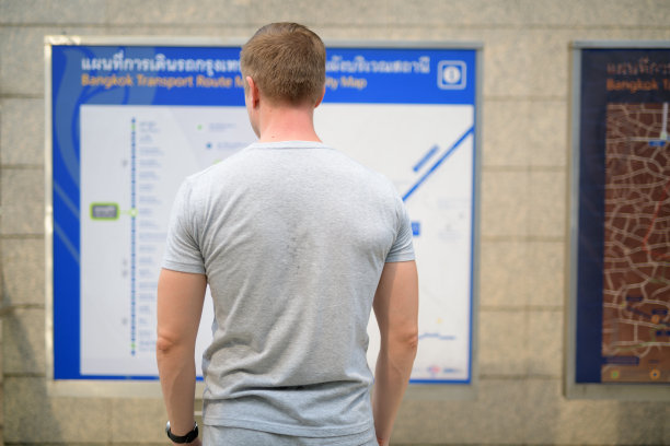 在曼谷火车站查看地图的年轻游客男子背影图片下载