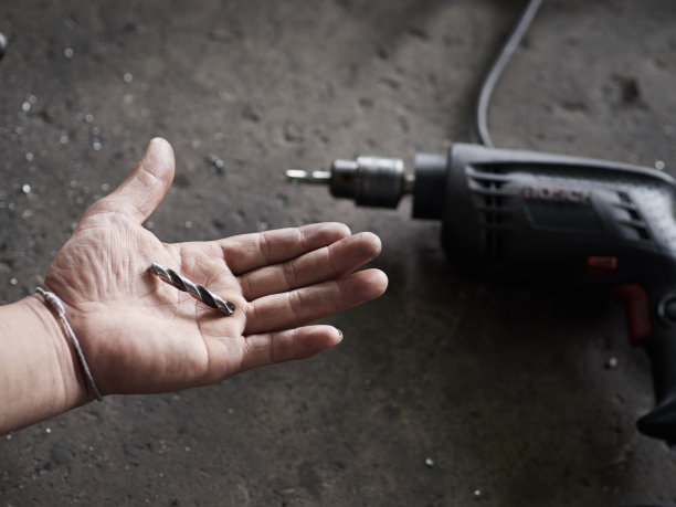 机修工在车库里被钻头损坏了。汽车服务理念。工作流程机械师在汽车修理厂。图片下载