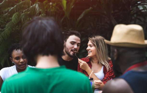 微笑的年轻夫妇聊天，在夏季户外派对和假日的概念喝和吃。图片下载