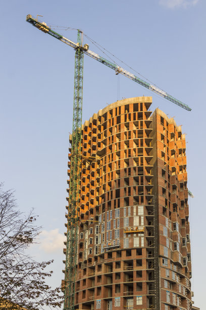 一幢高层建筑的施工，施工起重机。蓝色的天空背景图片下载