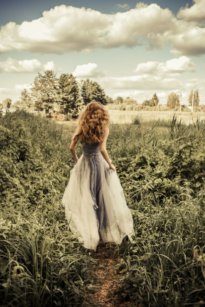 年轻美丽的女孩，一头卷发和一件长裙跑过一个精灵森林图片下载