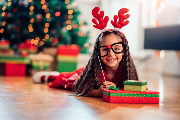 地板上躺着一个拿着圣诞装饰品的小女孩图片下载