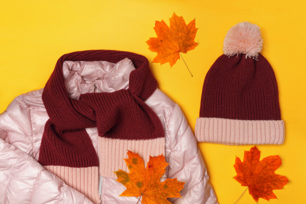 俯视图的组成温暖的儿童服装和秋天的树叶在黄色的背景图片下载