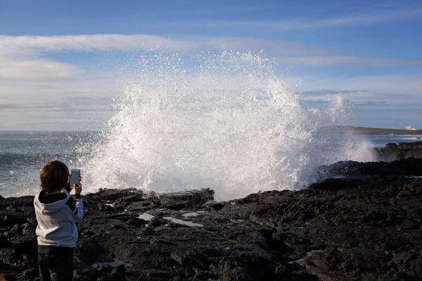 在冰岛的西南海岸，孩子们正在观看巨浪撞击岩石图片下载