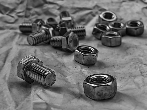 螺母和螺栓的抽象艺术设计背景放在垃圾表面背景上，黑白色调，模糊的灯光周围图片下载