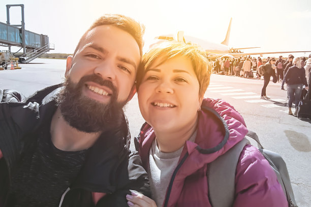 微笑的千禧夫妇在机场起飞时自拍图片下载