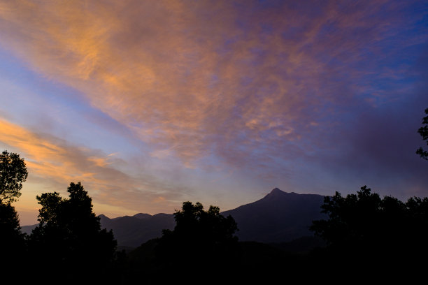 橙色的日出在多云的天空和黑色的山剪影在壮观的五颜六色的天空图片下载