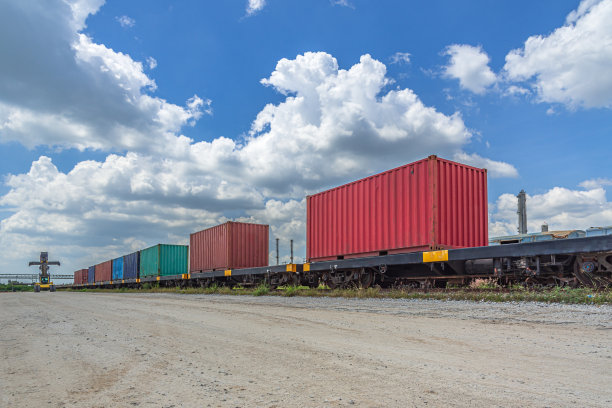在多云的天空下，在铁路站场装载集装箱。图片下载