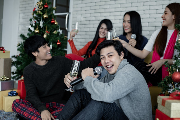 年轻的亚洲人欢聚一堂，在家里喝酒唱歌庆祝圣诞佳节。图片下载