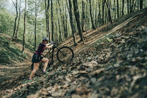 女运动员在森林里戴着头盔骑自行车上山的照片图片下载