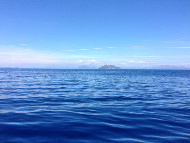 大海在群山和天空的映衬下一直延伸到地平线图片下载