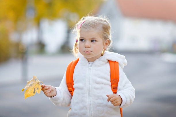 可爱的蹒跚学步的小女孩第一天去幼儿园。健康快乐的宝宝步行去幼儿园。孩子背着背包去城市街道上的托儿所，在户外图片下载