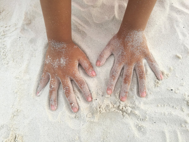 被沙子弄脏的孩子的手放在沙子上。图片下载