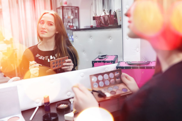 一个年轻的女孩在美容院化妆。镜子前的女孩正在化妆。美容沙龙。图片下载