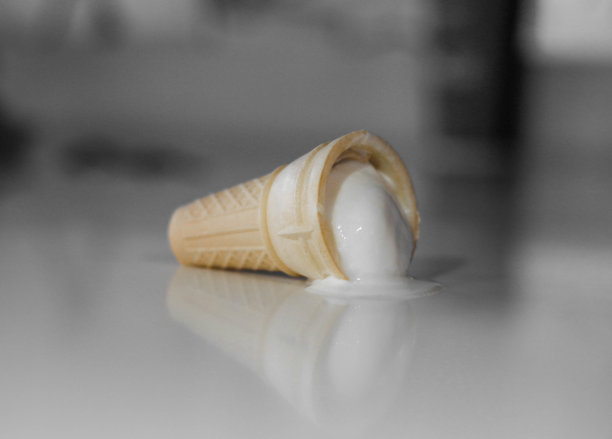 冰淇淋滴到了桌子上。蛋筒里的白色冰淇淋融化了。近距离图片下载