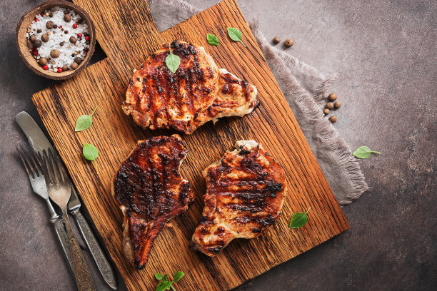 开胃的烤猪肉片在砧板上，黑色的乡村背景。俯视图，平放，复制空间。图片下载