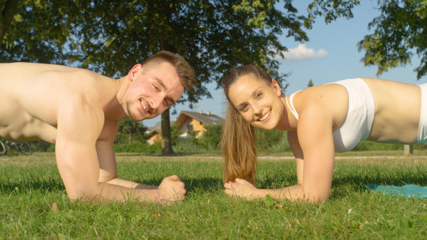 肖像:一对年轻夫妇在阳光明媚的公园里健身时看着镜头。图片下载