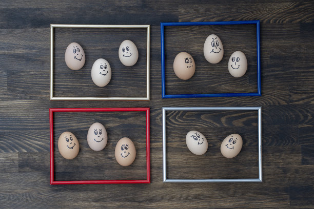 画框和许多有趣的鸡蛋微笑在黑暗的木墙背景。鸡蛋家庭情感面部肖像。概念有趣的食物图片下载