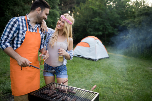 年轻夫妇和朋友微笑着在野营地烧烤图片下载
