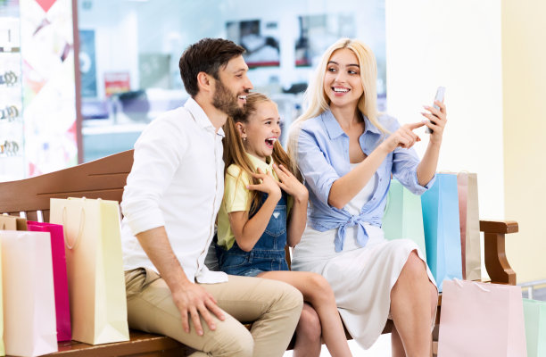 坐在购物中心的长凳上用手机搜索折扣的家庭图片下载