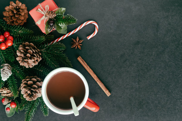 黑色花岗岩桌子装饰礼盒，松叶和松果，冬青球和杯巧克力在圣诞节的概念。背景在俯视图平铺与圣诞墙纸复制空间。图片下载