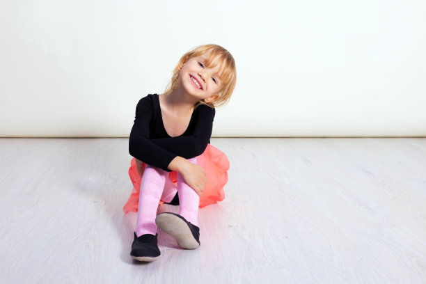 穿着粉红色芭蕾舞裙的小女孩。可爱的孩子在白色的工作室跳古典芭蕾。孩子们跳舞。一个班的年轻舞者。学龄前儿童坐在硬木地板上。为你的文本复制空间图片下载