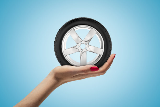 女性手握汽车车轮轮胎在蓝色背景图片下载