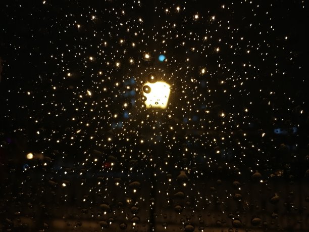玻璃和镜头上的雪滴闪耀着。一个黑暗的夜晚。图片下载