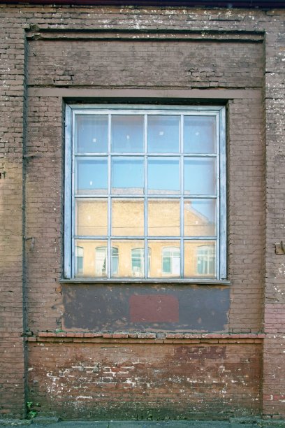 垂直的照片。砖墙和墙上的窗户。倒影在玻璃般的天空和对面的建筑中。图片下载