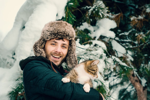 年轻人抱着猫，在下雪图片下载