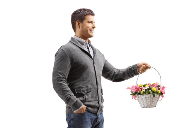 一个年轻人拿着一个装满花的篮子站在那里图片下载